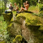 Hikers taking a break on top of a rock in a forest